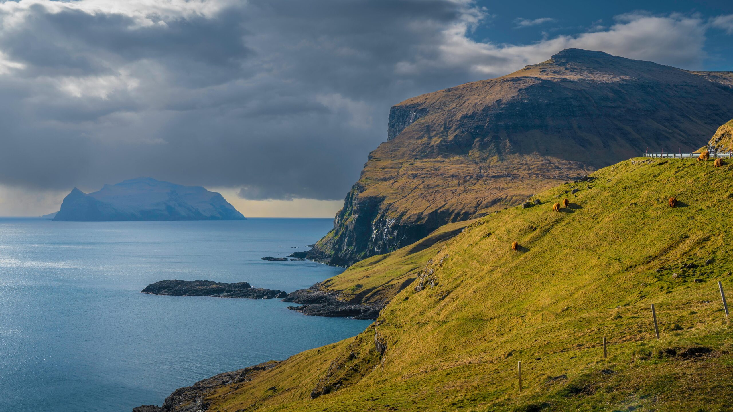 Atemberaubende Landschaft mit Klippen und Meer auf den Färöer-Inseln unter dramatischen Wolken.