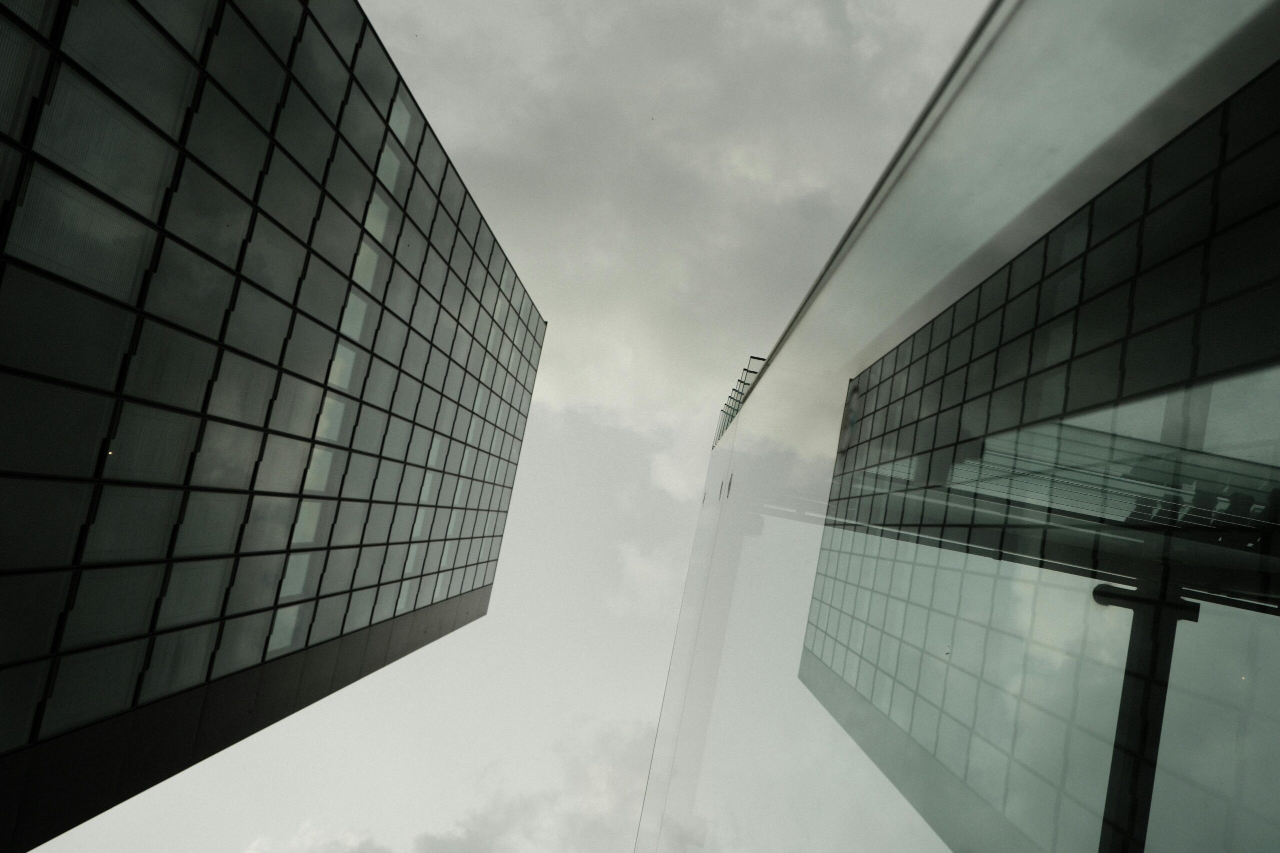 Perspektivische Aufnahme von zwei reflektierenden Wolkenkratzern vor einem bewölkten Himmel in Düsseldorf, Deutschland.