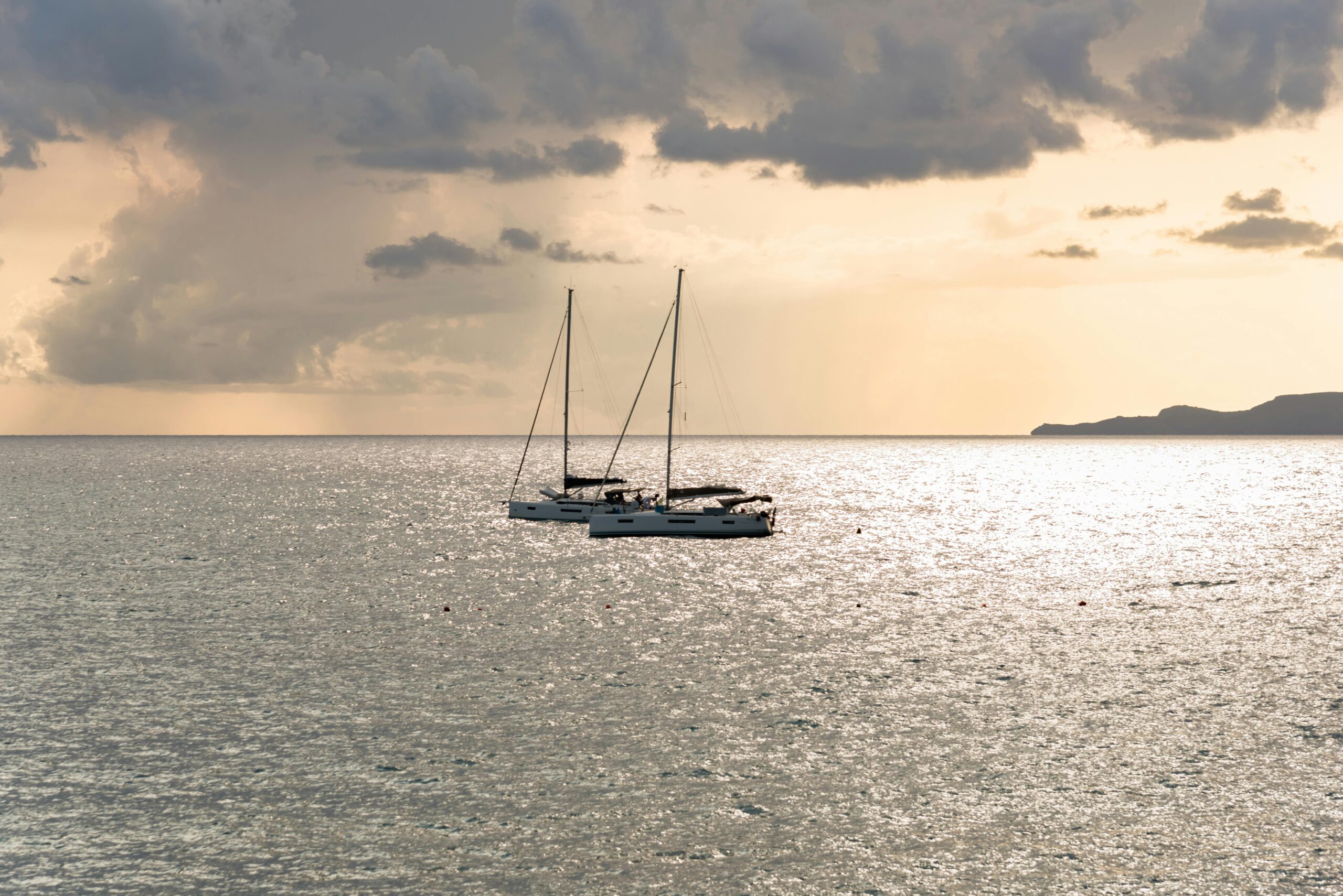 Zwei Yachten segeln bei Sonnenuntergang sanft auf dem schimmernden Wasser in Maratea, Italiens atemberaubender Küste.