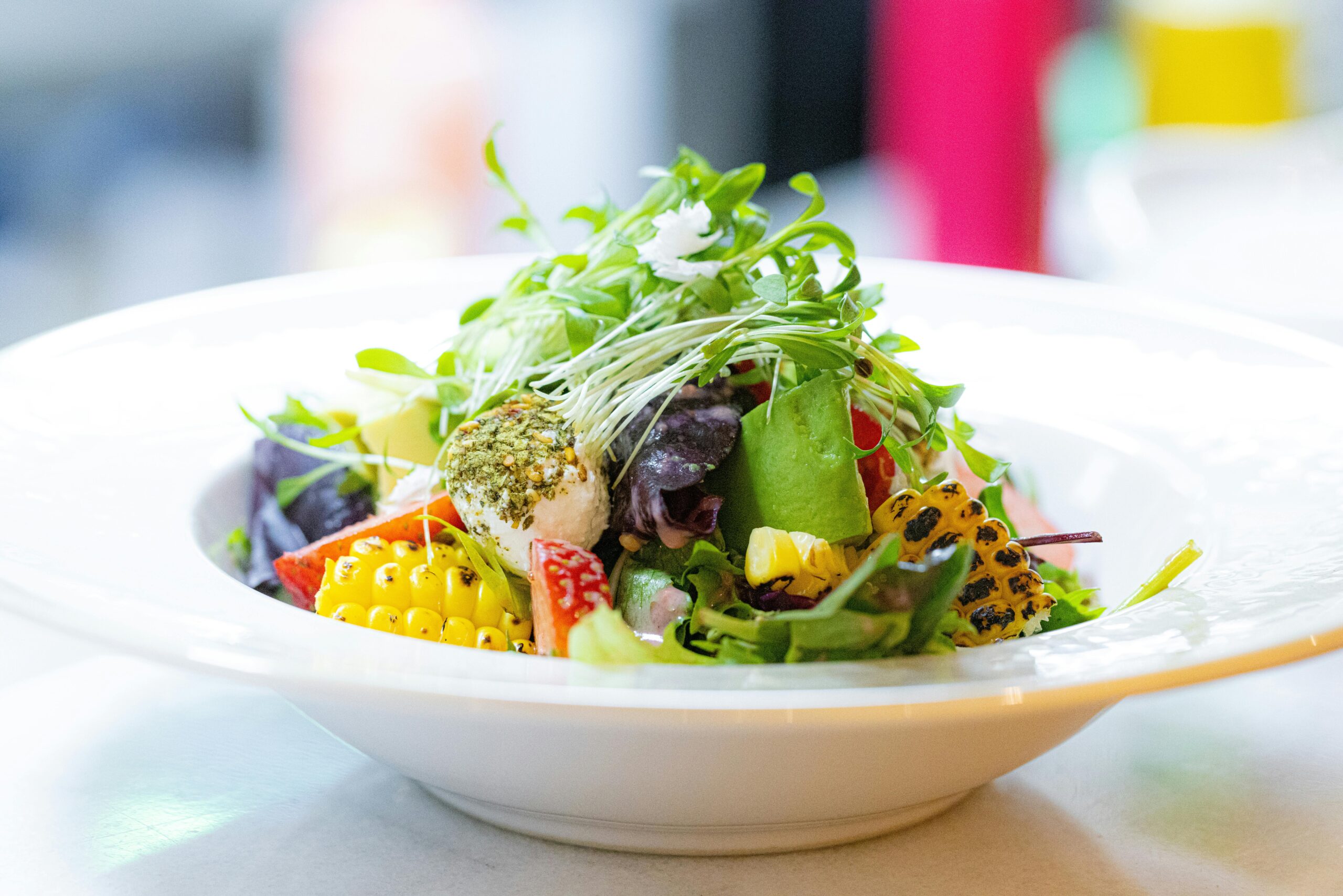 Bunter Gartensalat mit frischem Grün, Gemüse und Mais in einer weißen Schüssel.