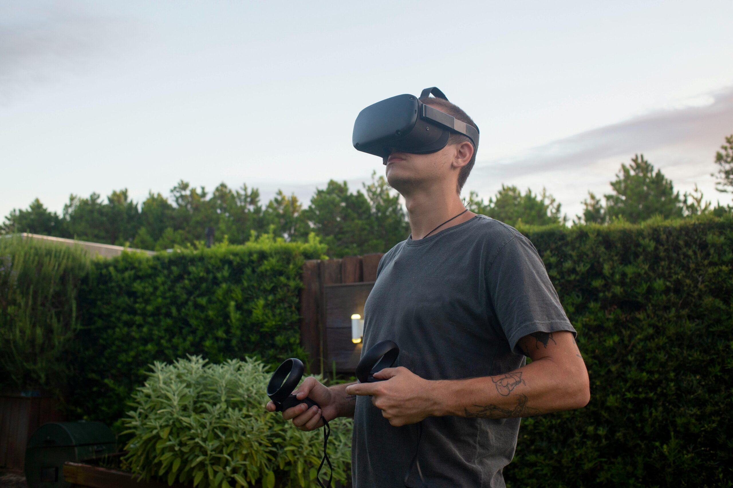Ein Mann mit VR-Headset und Controllern genießt ein Virtual-Reality-Erlebnis im Freien.